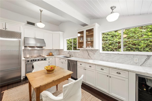 kitchen featuring backsplash, high quality appliances, hanging light fixtures, beverage cooler, and light stone counters