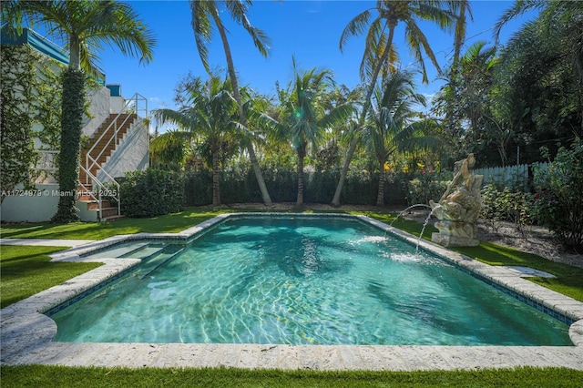 view of swimming pool featuring pool water feature and a yard