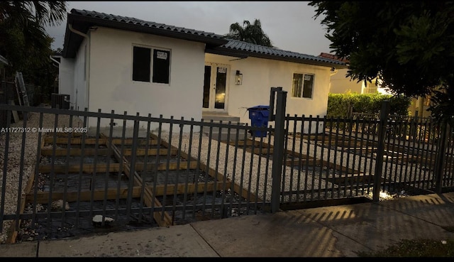 view of front facade featuring a tiled roof, stucco siding, and fence