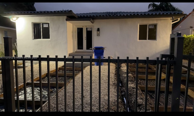 mediterranean / spanish home with a tiled roof, stucco siding, and fence