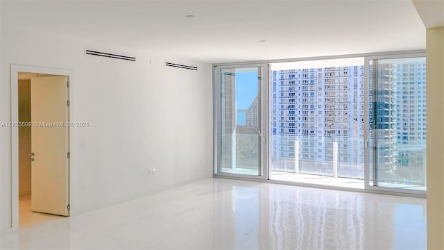 unfurnished room with a wall of windows and visible vents