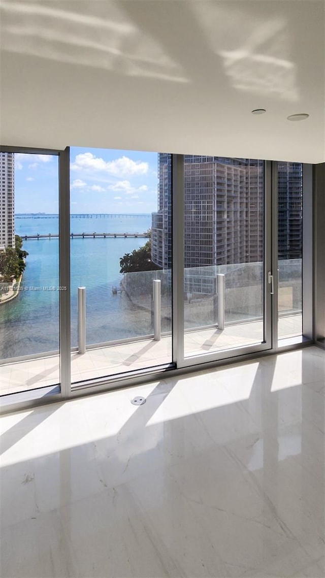 spare room featuring marble finish floor and a water view