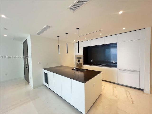 kitchen featuring white cabinets, sink, hanging light fixtures, a kitchen island with sink, and black stovetop