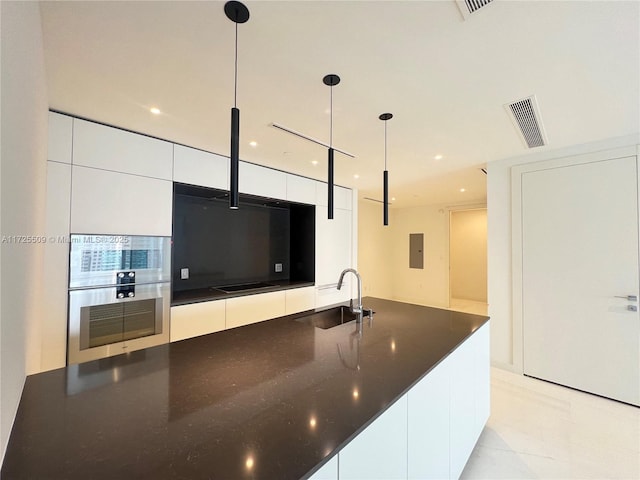 kitchen with electric panel, white cabinetry, pendant lighting, and sink