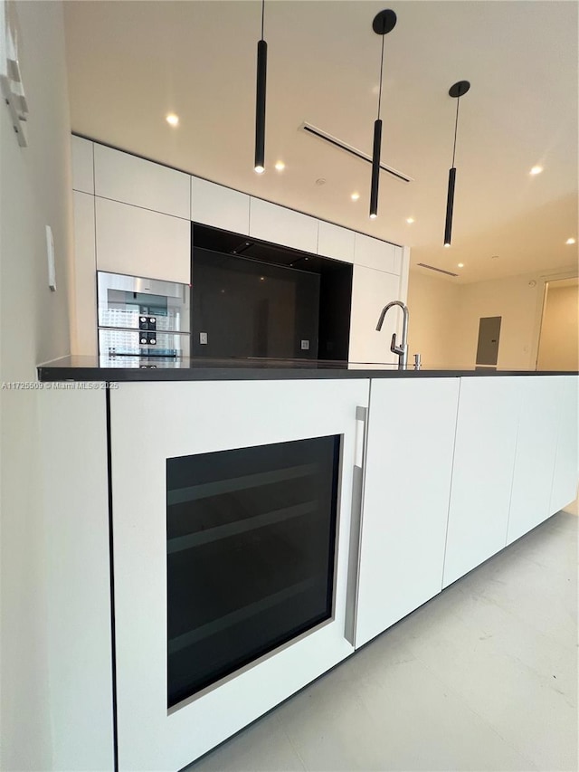 kitchen with decorative light fixtures, white cabinets, sink, and wine cooler