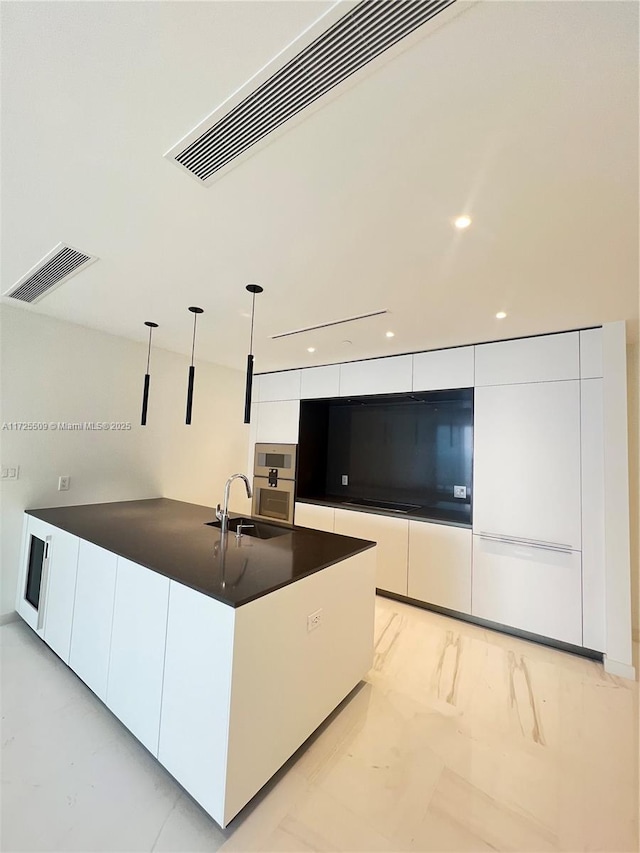 kitchen with decorative light fixtures, white cabinets, sink, and stainless steel oven