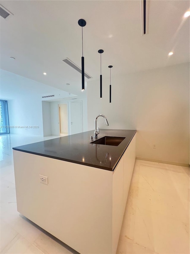 kitchen with decorative light fixtures, sink, and white cabinetry