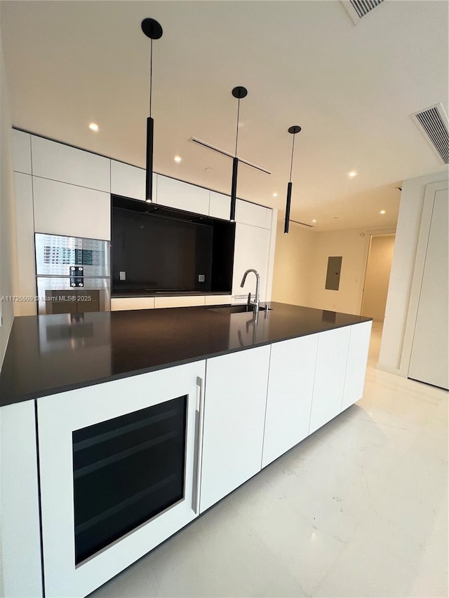 kitchen with sink, an island with sink, white cabinets, and decorative light fixtures