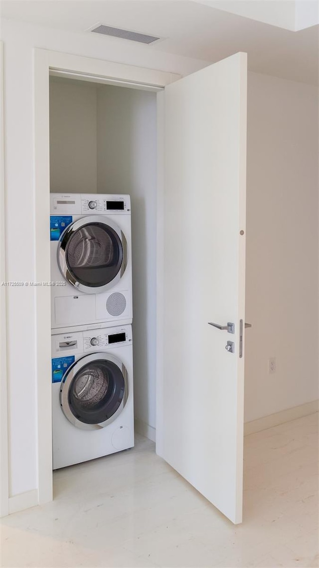 laundry room with stacked washing maching and dryer and visible vents