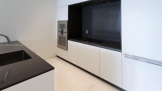 kitchen featuring white cabinetry, stainless steel oven, black electric cooktop, and a sink