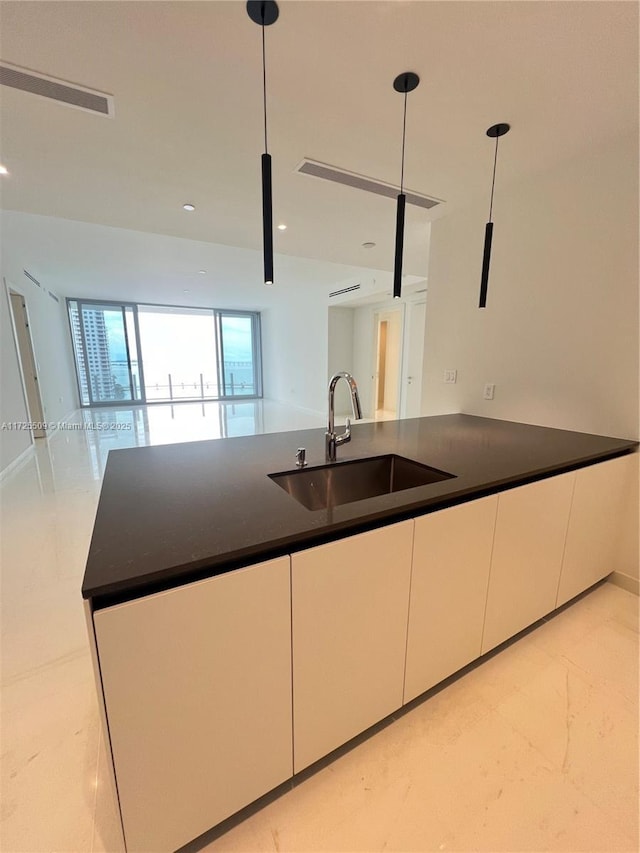 kitchen featuring decorative light fixtures, white cabinets, sink, and dark stone countertops