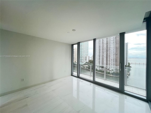 spare room featuring a water view and expansive windows