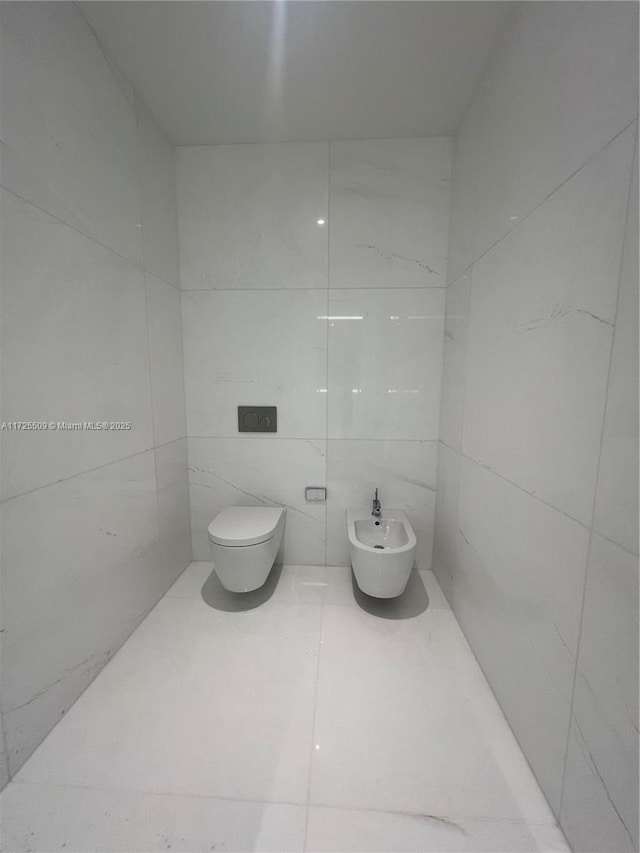 bathroom featuring toilet, tile patterned flooring, and a bidet