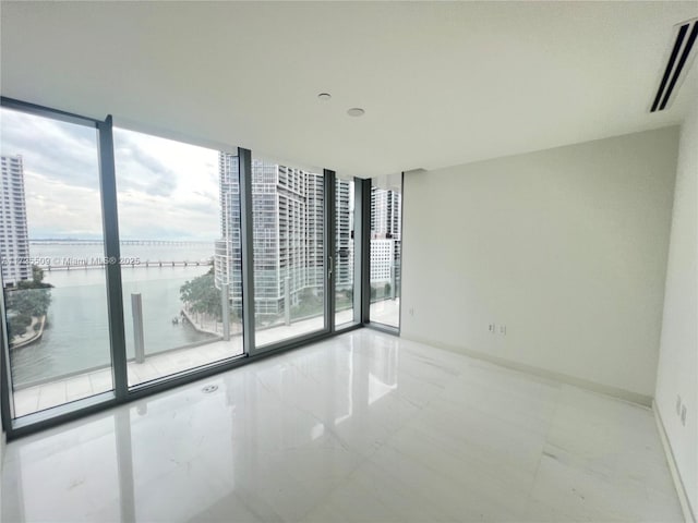 spare room with a water view and expansive windows