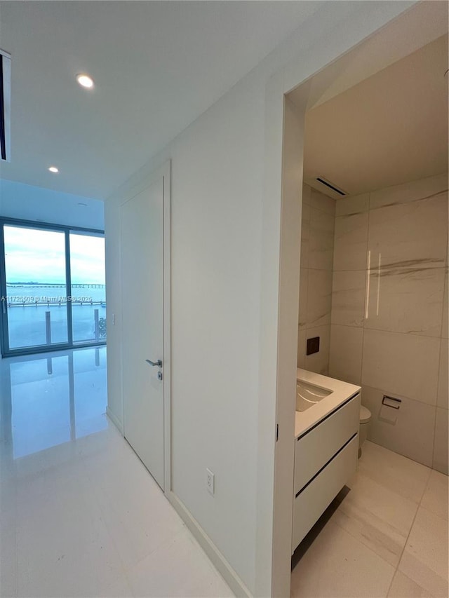 hall featuring a water view and light tile patterned floors