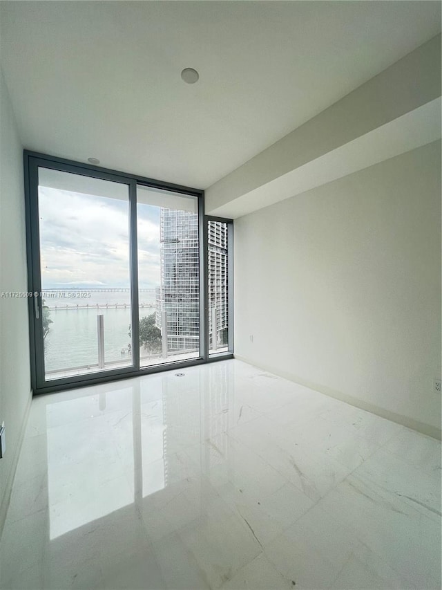 unfurnished room with a water view and floor to ceiling windows