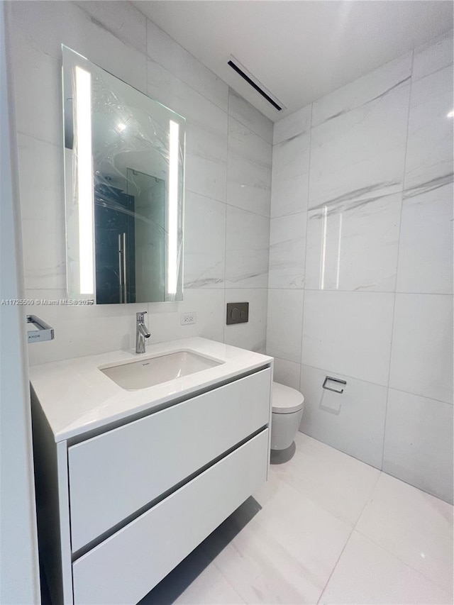 bathroom featuring tile patterned flooring, vanity, tile walls, and toilet