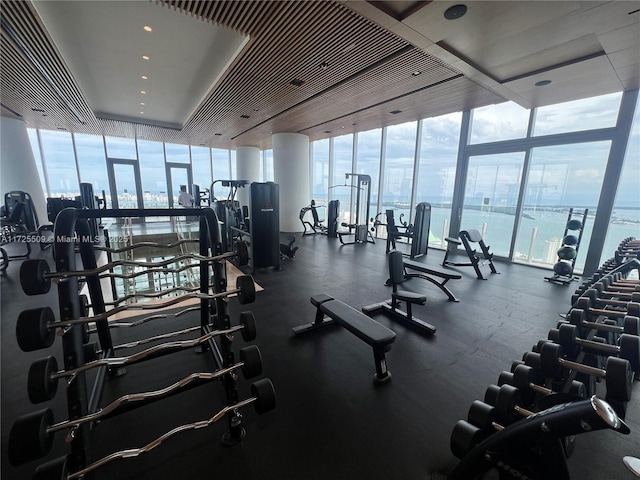 exercise room featuring a wall of windows and a water view