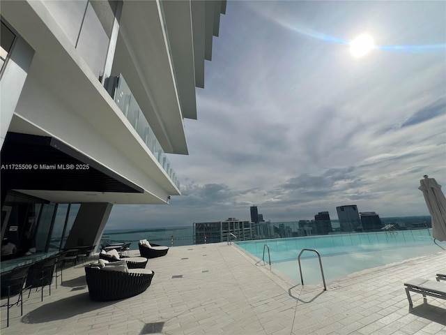 view of pool featuring a water view and a patio