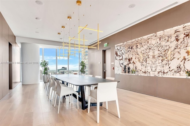 dining room with crown molding, a wall of windows, and light hardwood / wood-style flooring