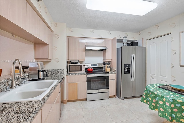 kitchen featuring light brown cabinetry, appliances with stainless steel finishes, sink, and a textured ceiling