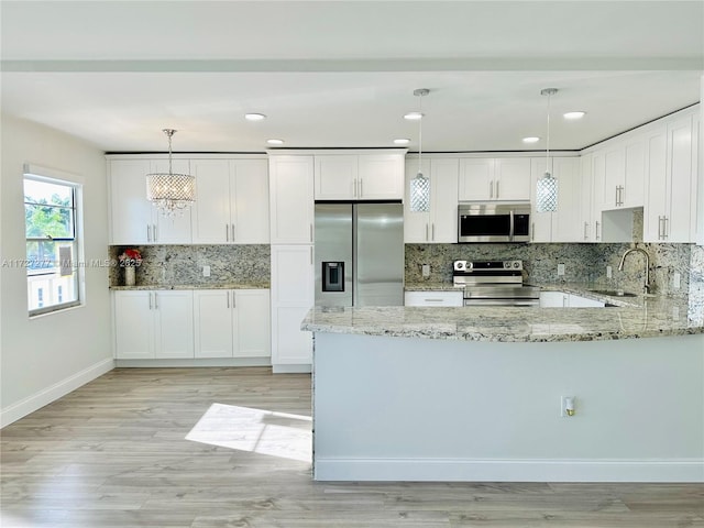 kitchen with pendant lighting, white cabinets, stainless steel appliances, sink, and light stone counters