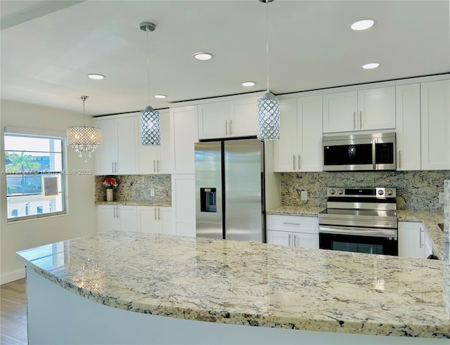 kitchen with decorative backsplash, white cabinets, pendant lighting, and appliances with stainless steel finishes