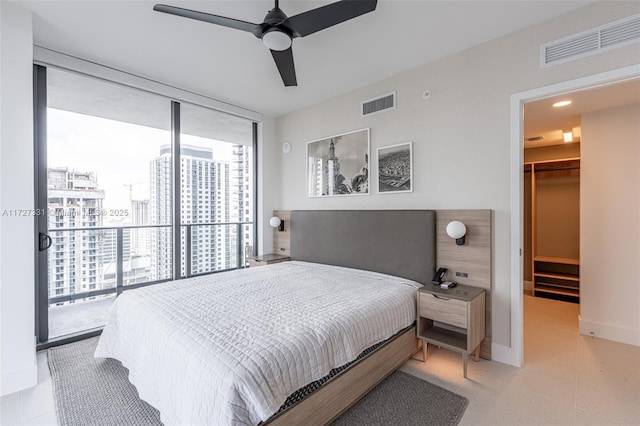 bedroom featuring ceiling fan, access to outside, a walk in closet, a wall of windows, and a closet