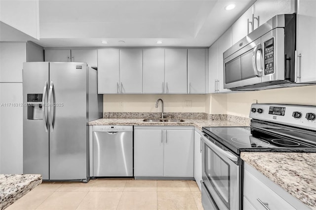 kitchen featuring sink, white cabinetry, appliances with stainless steel finishes, light tile patterned floors, and light stone counters