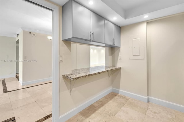 kitchen featuring ornamental molding, light tile patterned flooring, light stone counters, electric panel, and gray cabinetry