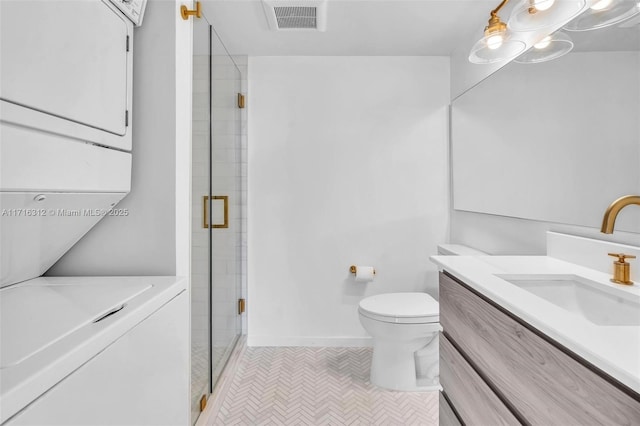 bathroom with stacked washer / drying machine, vanity, toilet, tile patterned floors, and a shower with door