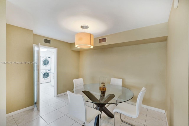 dining room featuring stacked washer / dryer and light tile patterned flooring