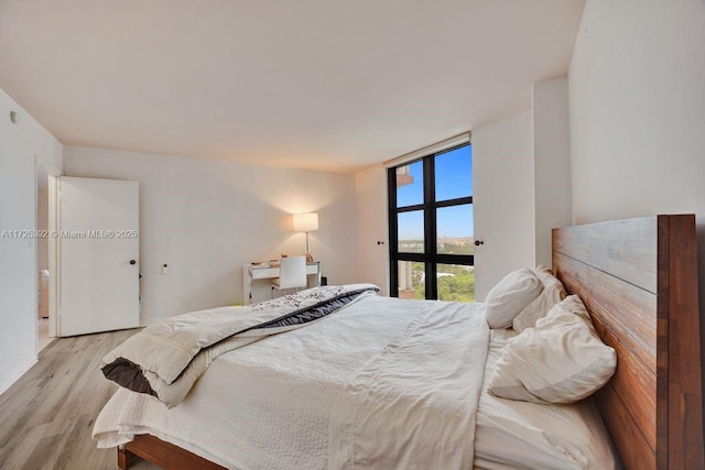 bedroom featuring light wood-type flooring and floor to ceiling windows