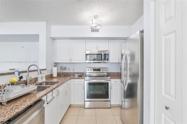 kitchen featuring light tile patterned floors, appliances with stainless steel finishes, sink, and white cabinetry