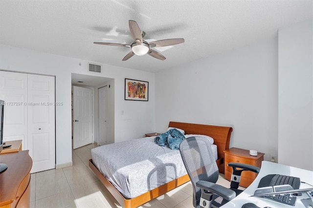 bedroom with ceiling fan, light tile patterned floors, a closet, and a textured ceiling