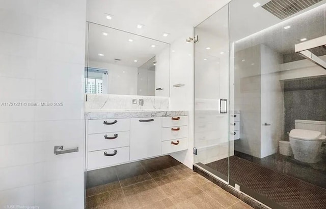 bathroom with a shower with door, vanity, and toilet