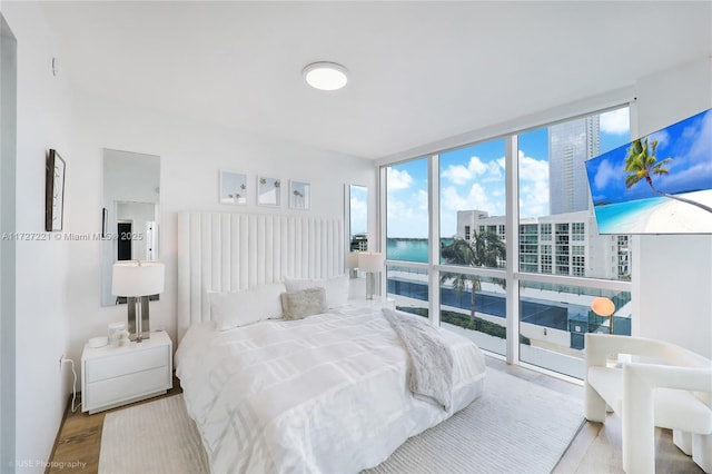 bedroom with floor to ceiling windows and light hardwood / wood-style flooring