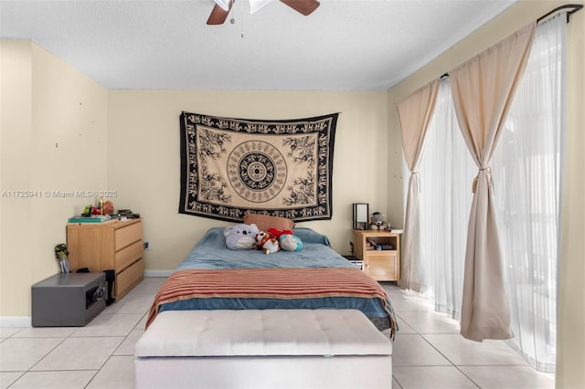 bedroom featuring ceiling fan, light tile patterned floors, and a textured ceiling