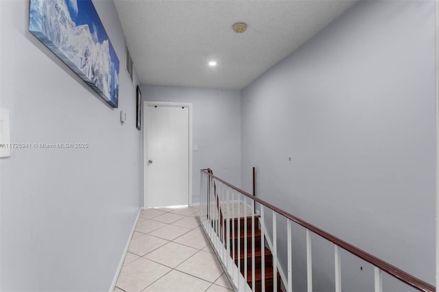 hall with a textured ceiling and light tile patterned floors