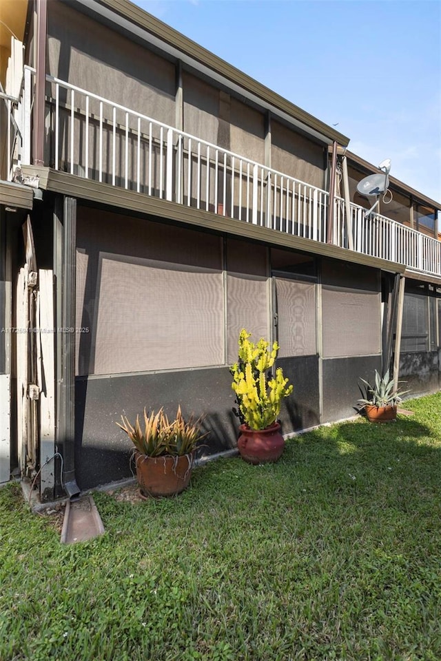 back of house featuring a balcony and a yard