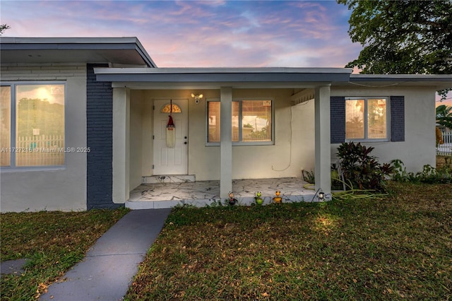 exterior entry at dusk featuring a lawn