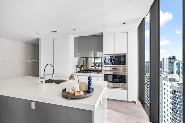 kitchen with light stone countertops, sink, white cabinetry, and appliances with stainless steel finishes