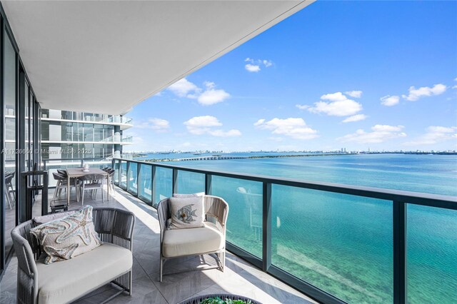 bedroom featuring a water view, expansive windows, light parquet floors, and multiple windows