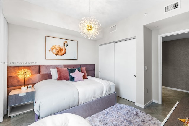 bedroom featuring a closet, a chandelier, and dark parquet floors