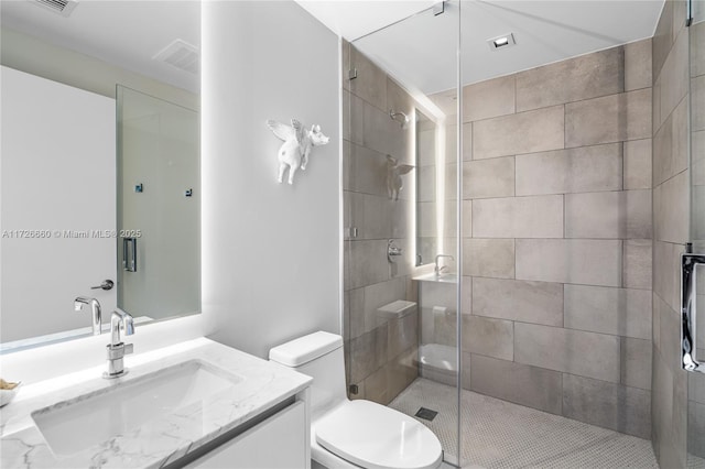 bathroom featuring toilet, vanity, and a shower with shower door