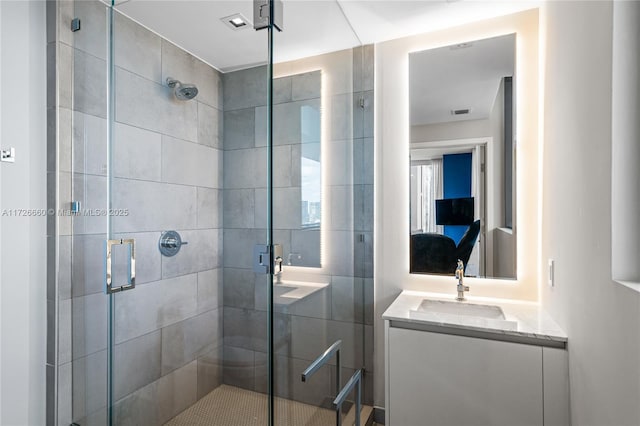 bathroom featuring a shower with shower door and vanity