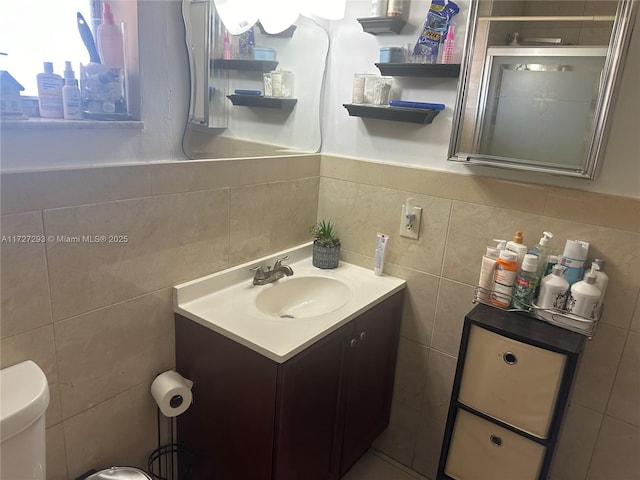 bathroom with tile walls, toilet, vanity, and tasteful backsplash