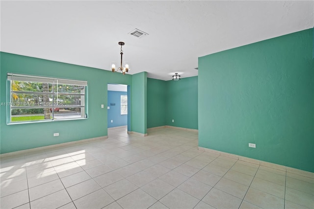 spare room featuring an inviting chandelier, light tile patterned flooring, and plenty of natural light