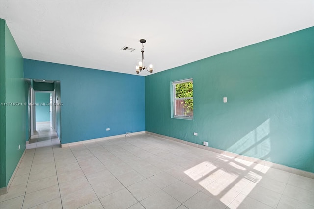 spare room with an inviting chandelier and light tile patterned floors