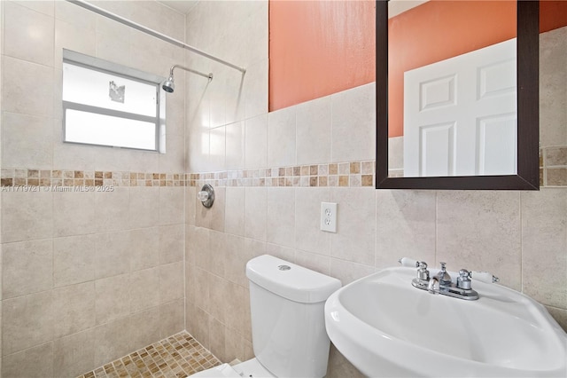 bathroom featuring sink, tile walls, tiled shower, and toilet